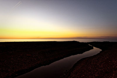 Scenic view of beach against clear sky during sunset