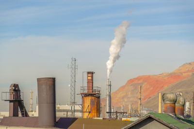 Smoke emitting from factory against sky