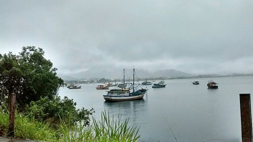 Boats in sea against cloudy sky