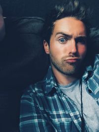 Close-up of young man making face on sofa at home