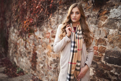 Portrait of woman standing against wall