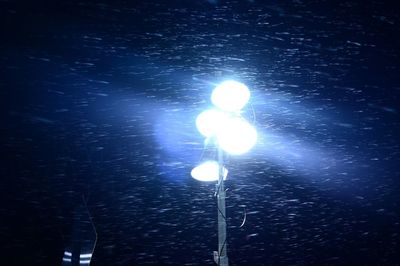 Low angle view of illuminated lights against sky at night