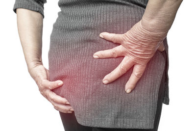 Midsection of woman massaging buttocks against white background