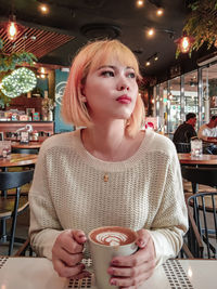 Mid adult woman drinking coffee at restaurant