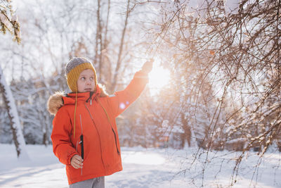 Young woman standing against bare tree during winter