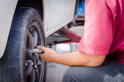 Midsection of man repairing car wheel