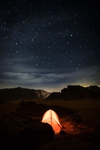 Illuminated tent on field against star field