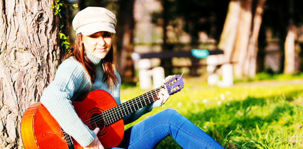 Portrait of woman playing guitar at park