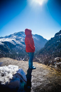 Rear view of person standing on snowcapped mountain