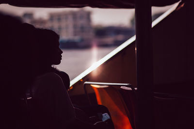 Side view of silhouette man sitting in window