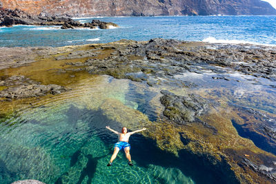 High angle view of woman standing on rock at sea