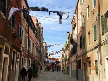 Rear view of couple walking on street amidst buildings in city