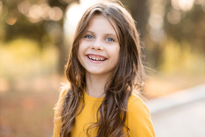 Laughing child girl 5-6 year old with long blonde hair over nature autumn background.