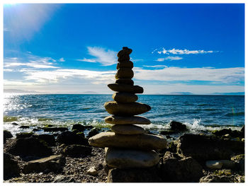 Stack of pebbles on beach against sky