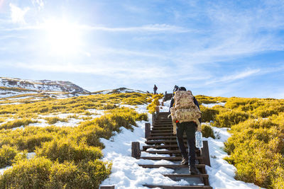 Rear view of people on snow covered mountain against sky