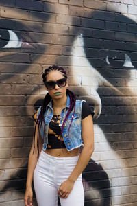 Young woman standing against brick wall