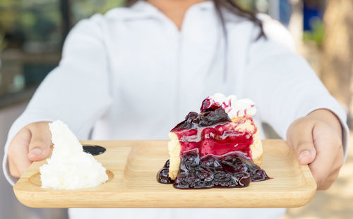Midsection of man holding ice cream on table