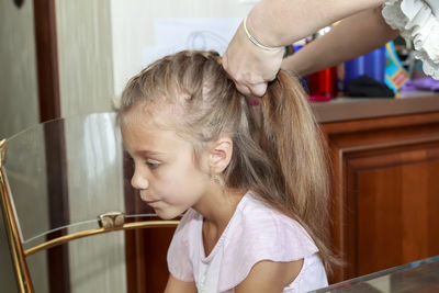 Cropped hand of mother tying daughters hair