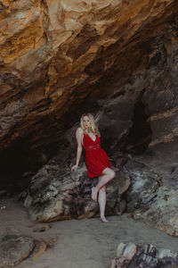 Full length portrait of woman standing against rock formation