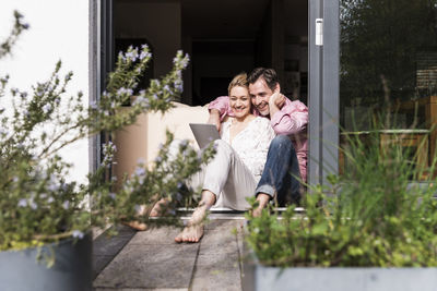 Mature couple relaxing together at open terrace door using tablet