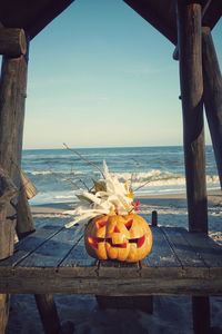 Pumpkins on table by sea against sky
