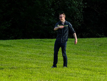 Smiling man holding plastic disc while standing on grass