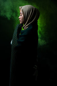 Side view of woman in hijab over black background