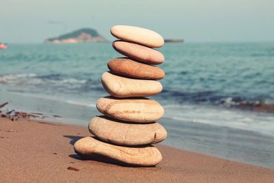 Stack of pebbles on beach against sky