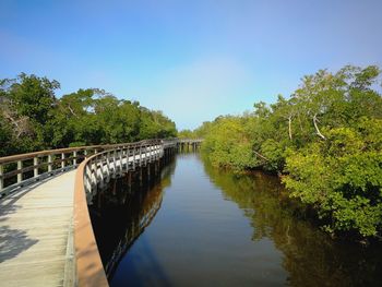 Footbridge over river against clear sky