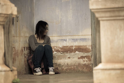 Full length of woman sitting against building