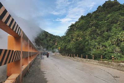 Road along the side of a sulfur mountain amidst trees against sky in the province