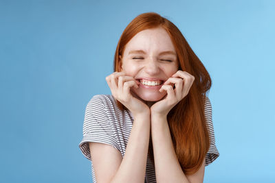 Portrait of a smiling young woman against blue background