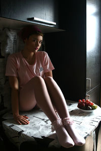 Portrait of beautiful young woman sitting on table at home