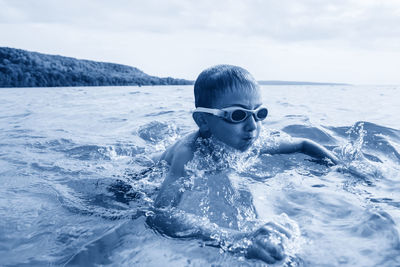 Close-up of boy sea against sky