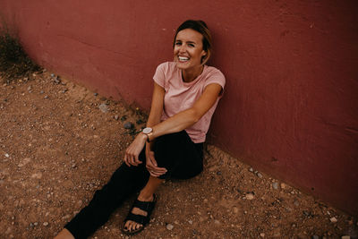 Portrait of woman sitting against wall