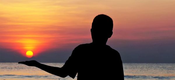 Silhouette man standing at beach during sunset