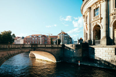 Arch bridge over river against buildings in city