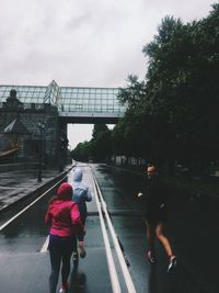 Rear view of woman walking on road in rain