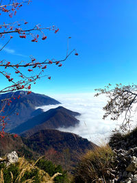 Scenic view of mountains above the clouds against blue sky