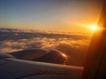 Airplane wing against sky during sunset