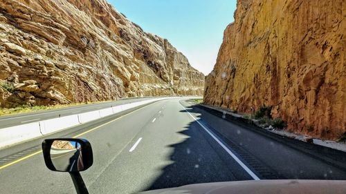 Road amidst mountains seen through car windshield