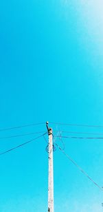 Low angle view of electricity pylon against blue sky