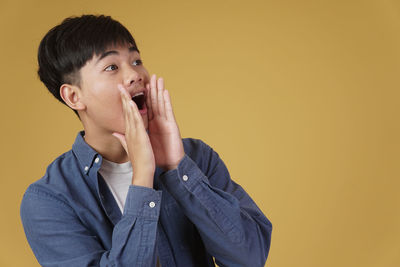 Portrait of young man looking away against wall