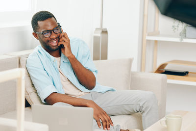 Young woman using mobile phone while sitting at home