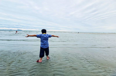 Rear view of man at beach against sky