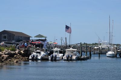 Sailboats in harbor by buildings against clear sky