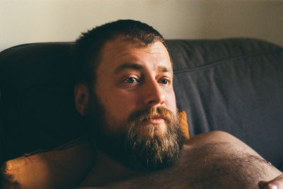 Man looking away while lying on sofa at home