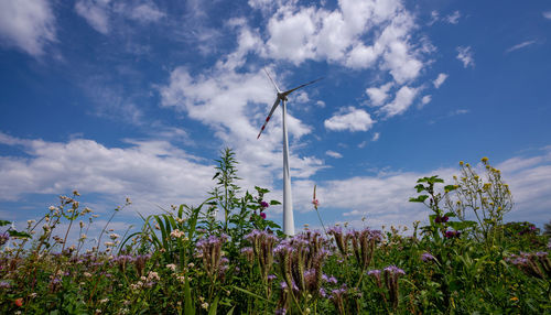 Low angle view of wind turbines on field against sky