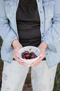 Hands of elderly woman holding a bowl of ripe cherries