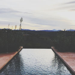 Scenic view of swimming pool by river against sky